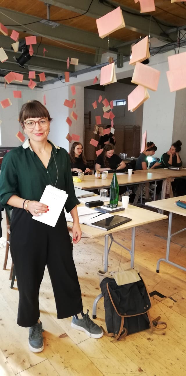 Uljana Wolf steht lächelnd und hält ein Papier in der Hand.