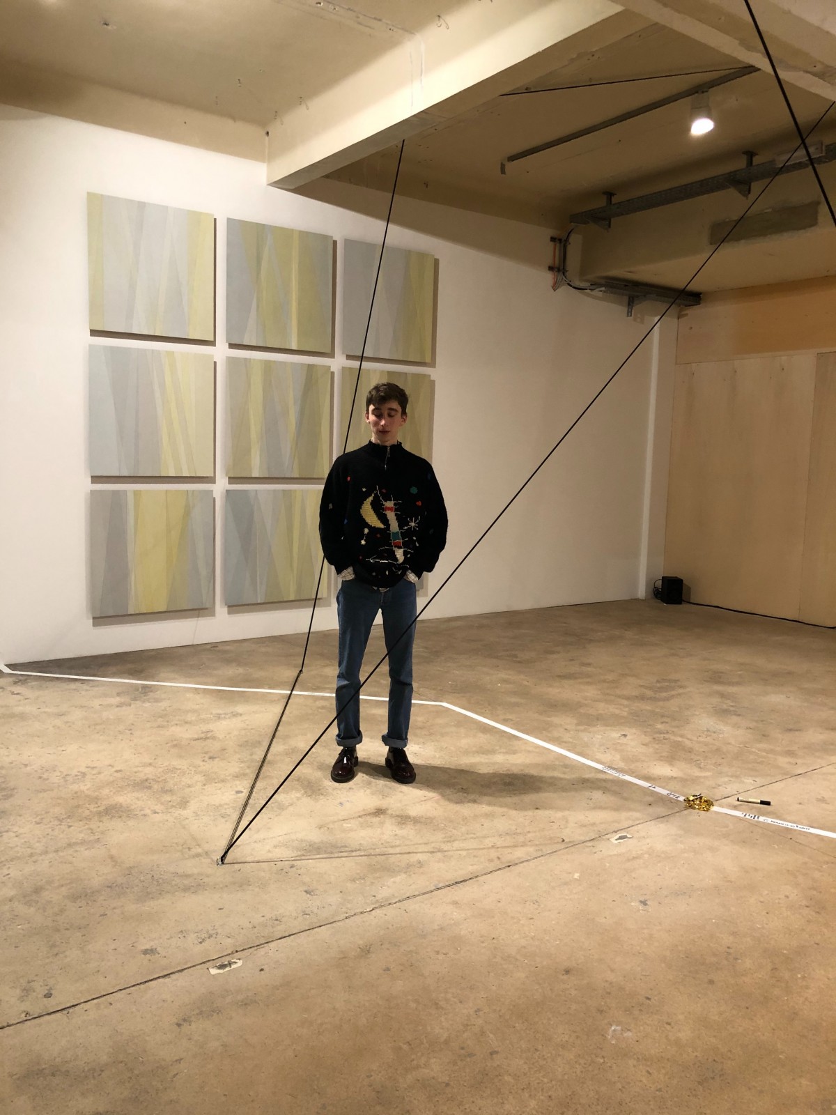 Felix steht in einem Raum des Künstlerhaus 1050, im Hintergrund Malereien.