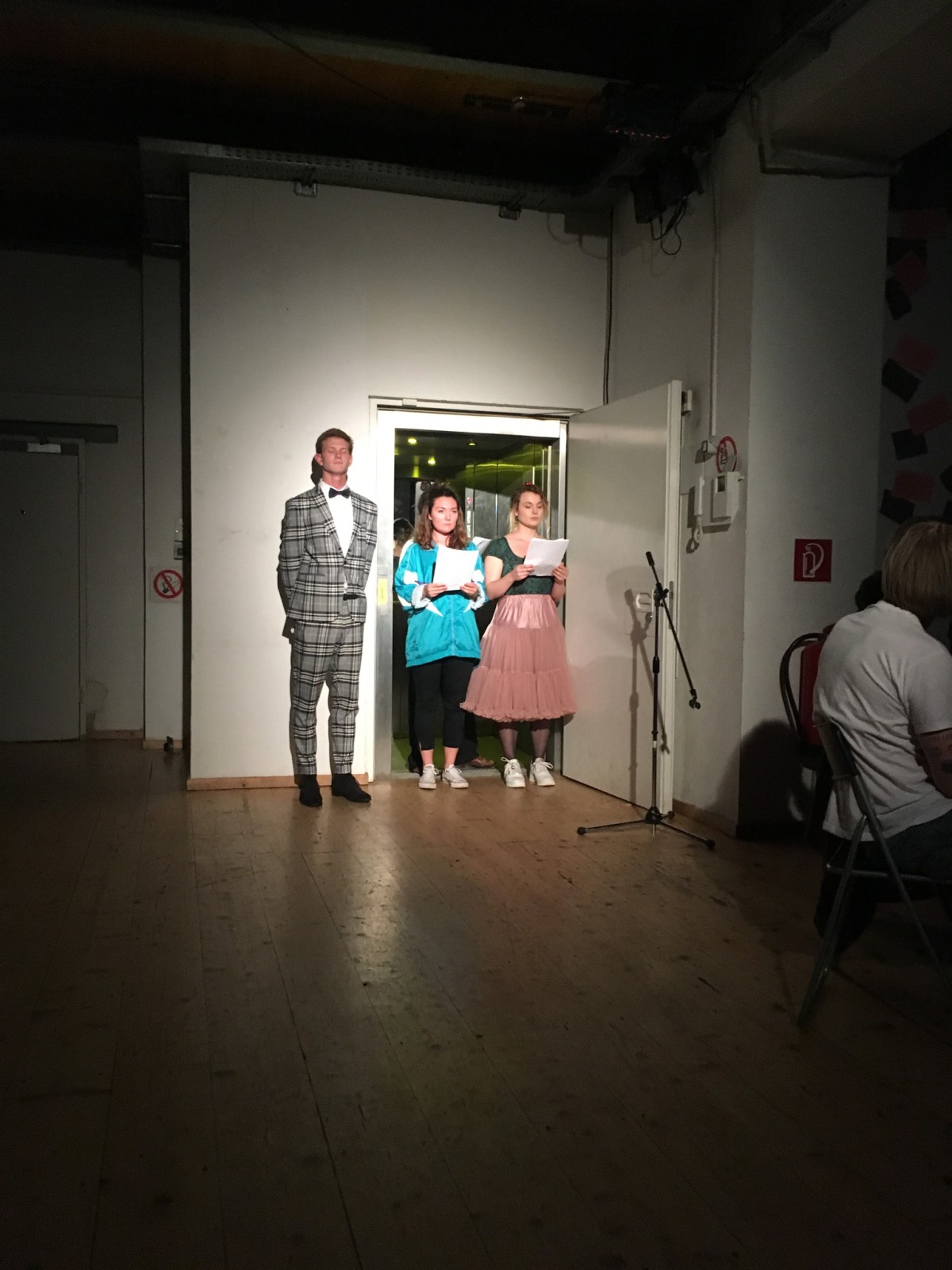 Drei Schauspieler*innen stehen im Spotlight und lesen Texte vor.